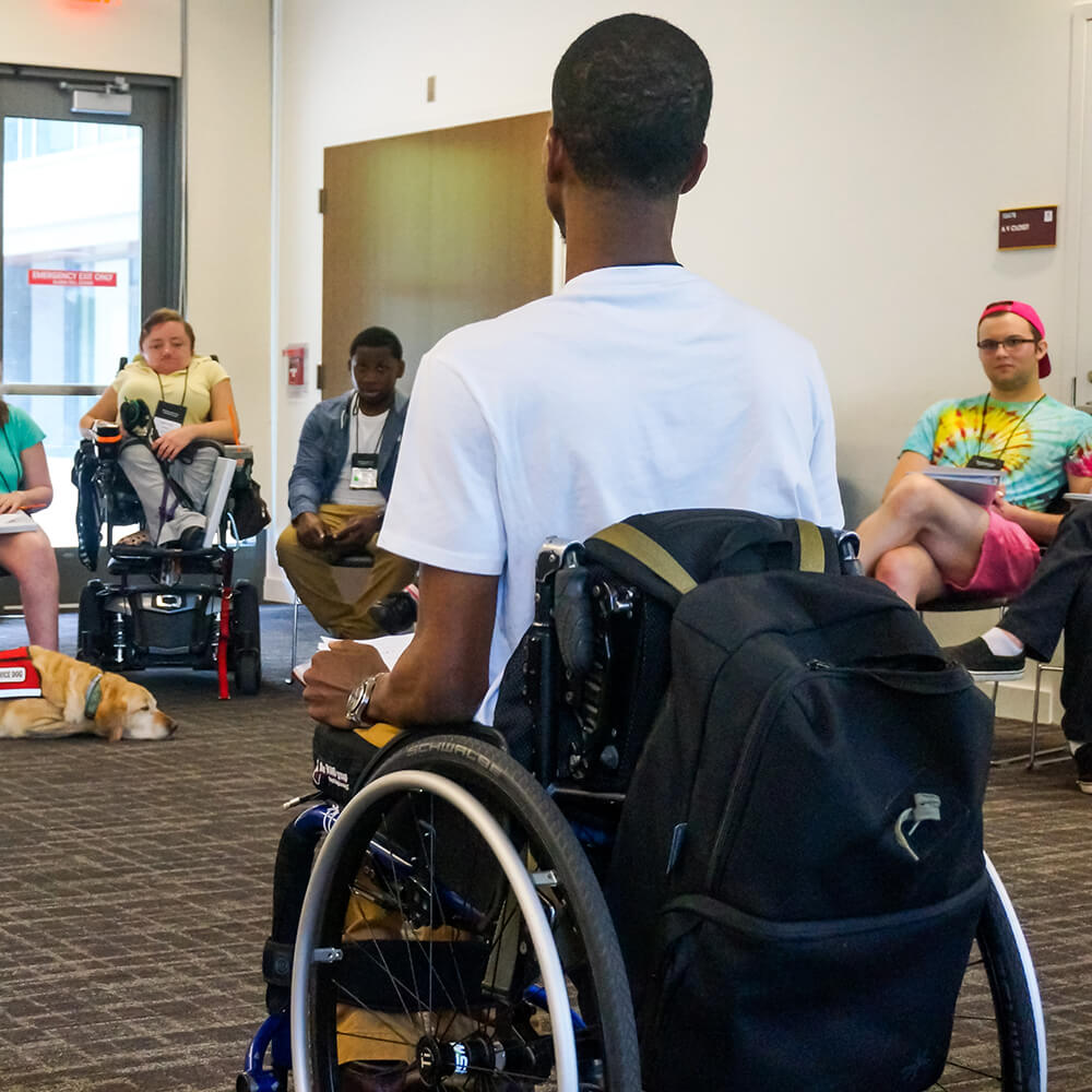 A young man in a wheelchair leads a team of professionals