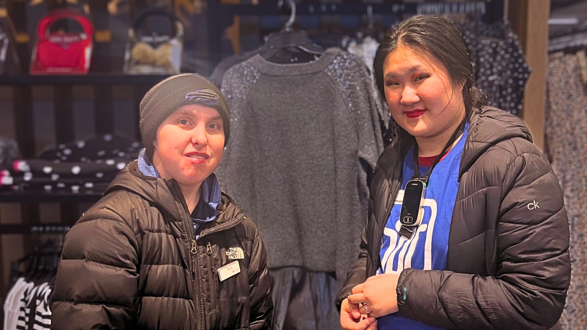 A mentor and mentee are standing next to each other at a clothing display at Macy's.