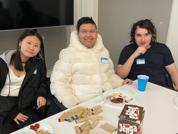 Three PYD participants are sitting at a board game table, with Jenga tiles spread across the table.