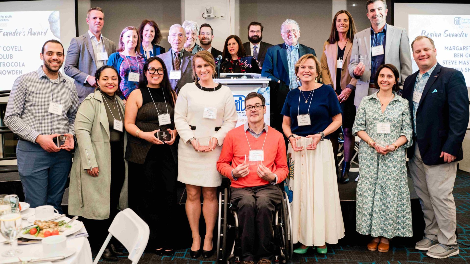 A group of honorees are standing at the Party4PYD stage, holding their awards