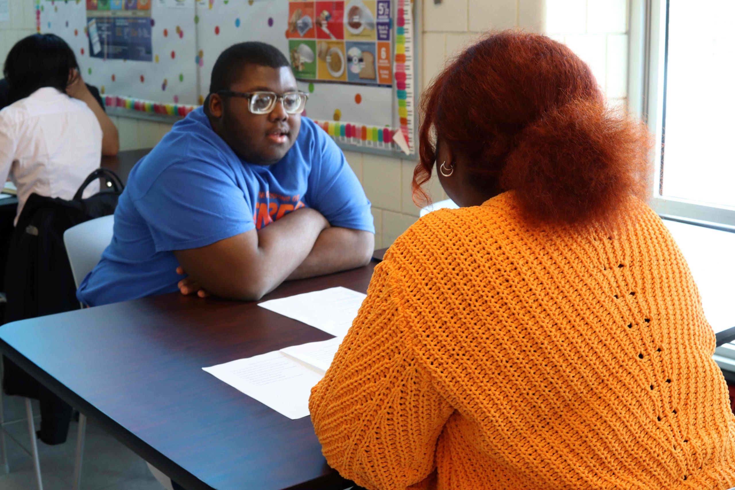 A student (left) sits at a table with a PYD staff member (right) at a a mock interview 