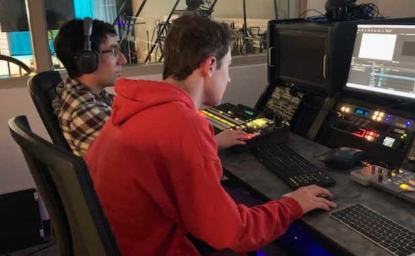 Kyle sits at a work station, editing.