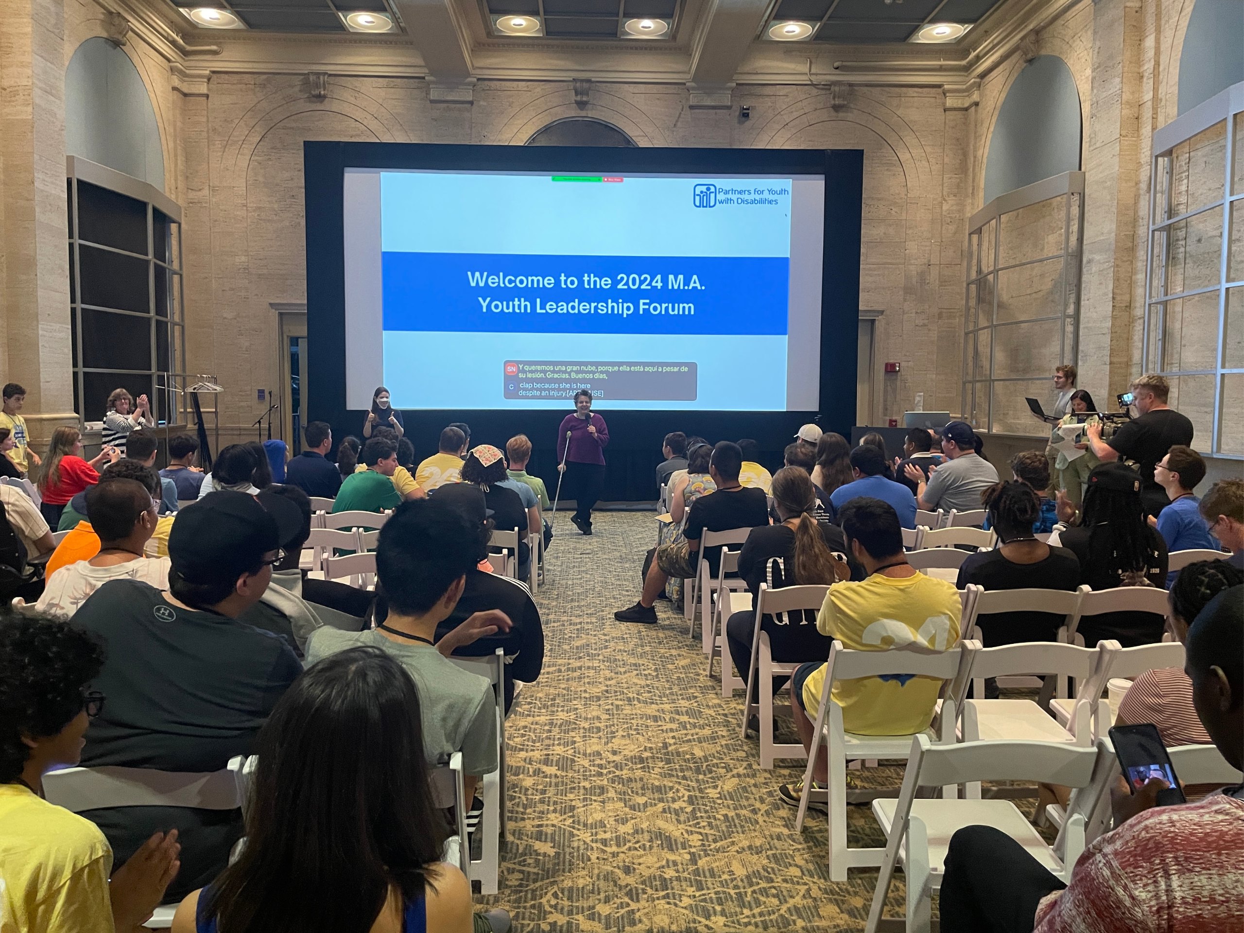 Participants watch a presentation on a large screen.