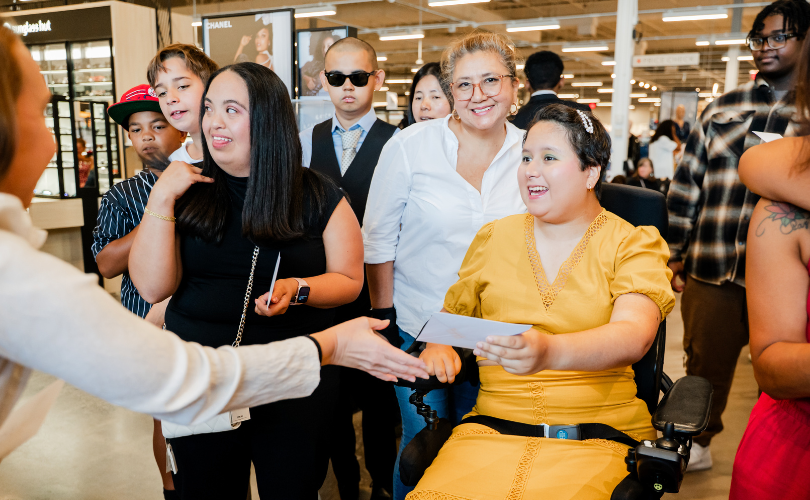 PYD participants are given an envelope with Macy's gift cards, and are smiling as they receive them.