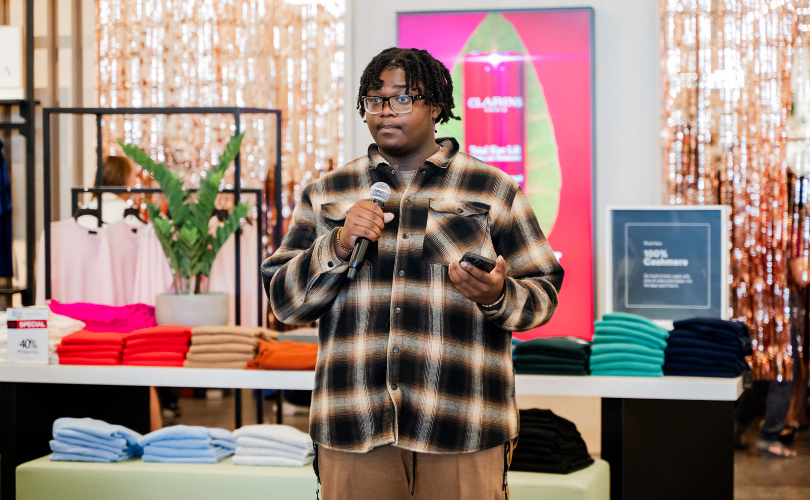Host, Amir Harper, speaks into a microphone, emceeing the event.