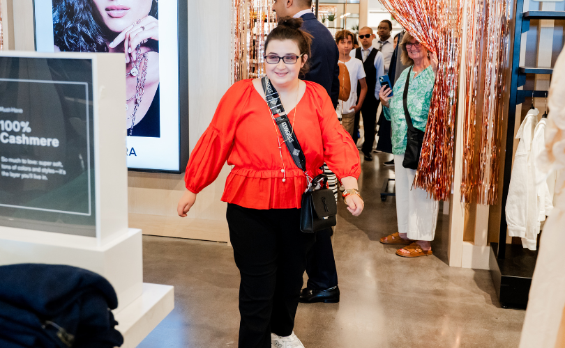 A PYD participant in a bright orange top walks out onto the runway
