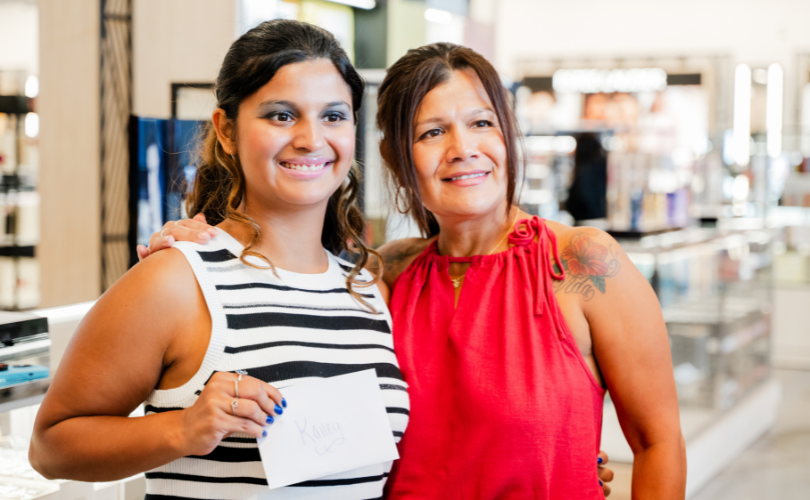 A PYD participant and her mother hold an envelope, which contains Macy's gift cards.
