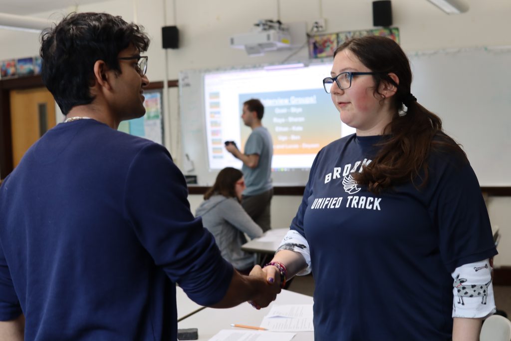 A student and volunteer shake hands at a mock interview