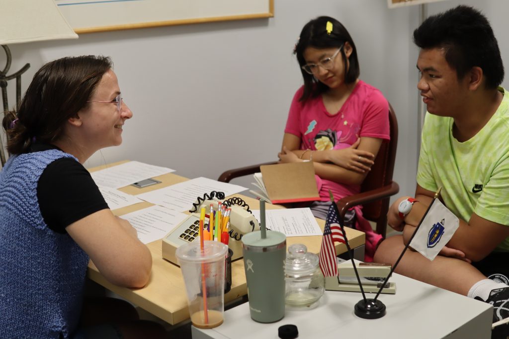 PYD staff member sits across from two students during a mock interview.